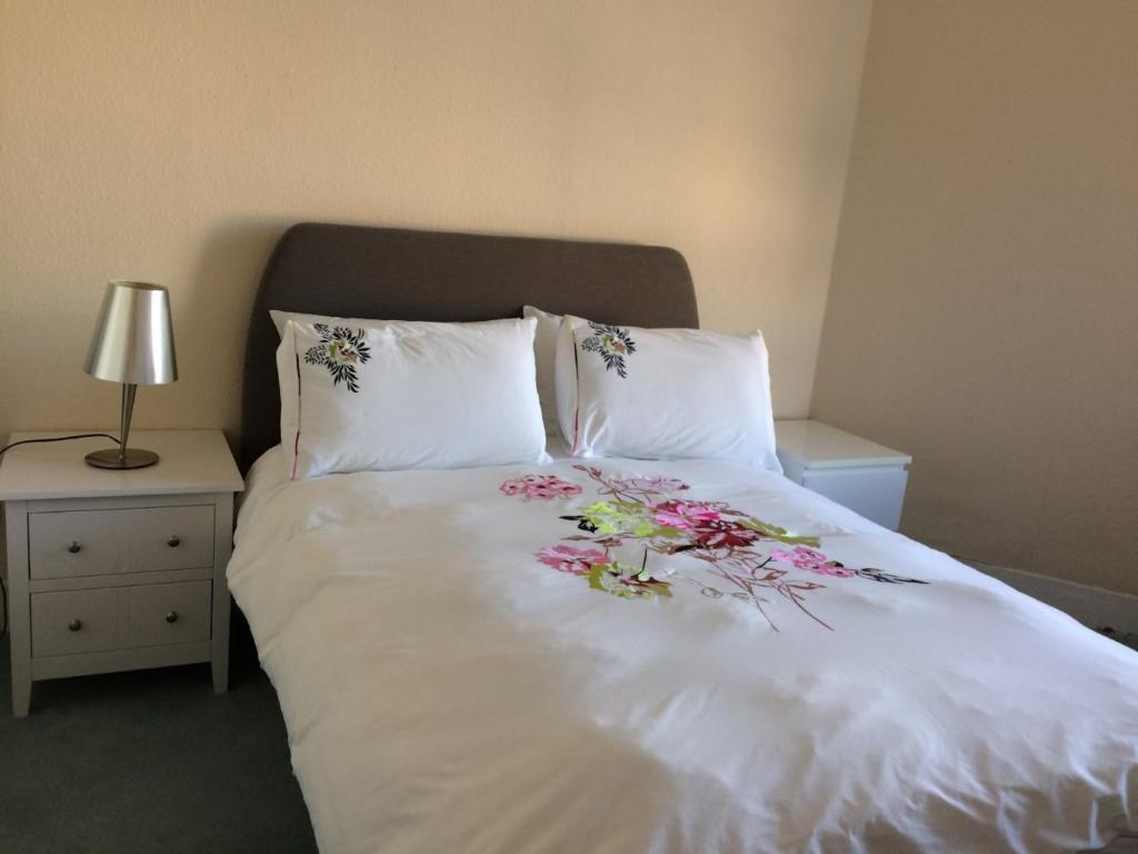 Una cama blanca con flores encima. en Royal Mile Apartment 3rd Floor No Lift en Edimburgo