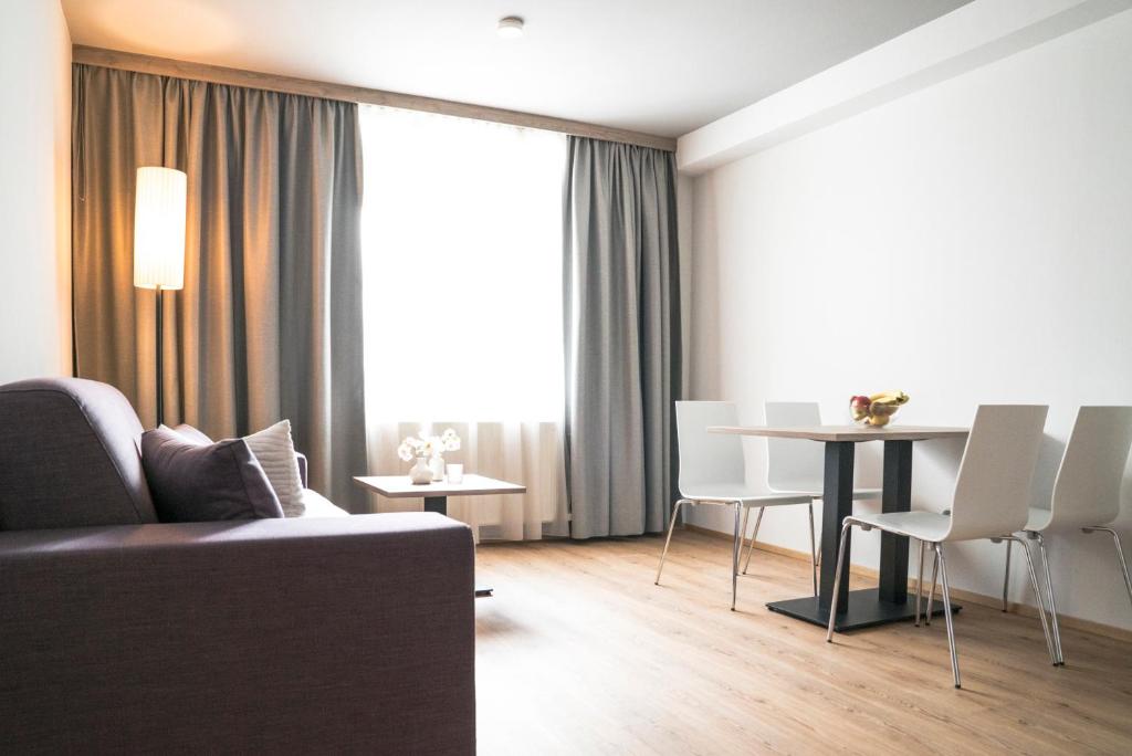 een woonkamer met een bank en een tafel en stoelen bij Daxburg Apartments in Innsbruck