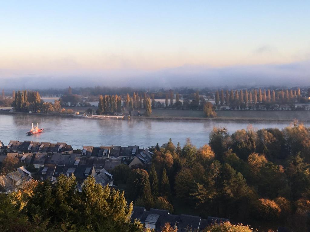 a river with houses and a boat in the water at VUE SEINE Chambre Panorama in La Bouille