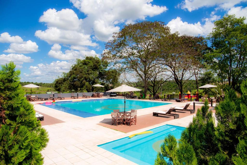 una piscina con mesas, sillas y sombrillas en 7 Saltos Resort en Salto del Guairá
