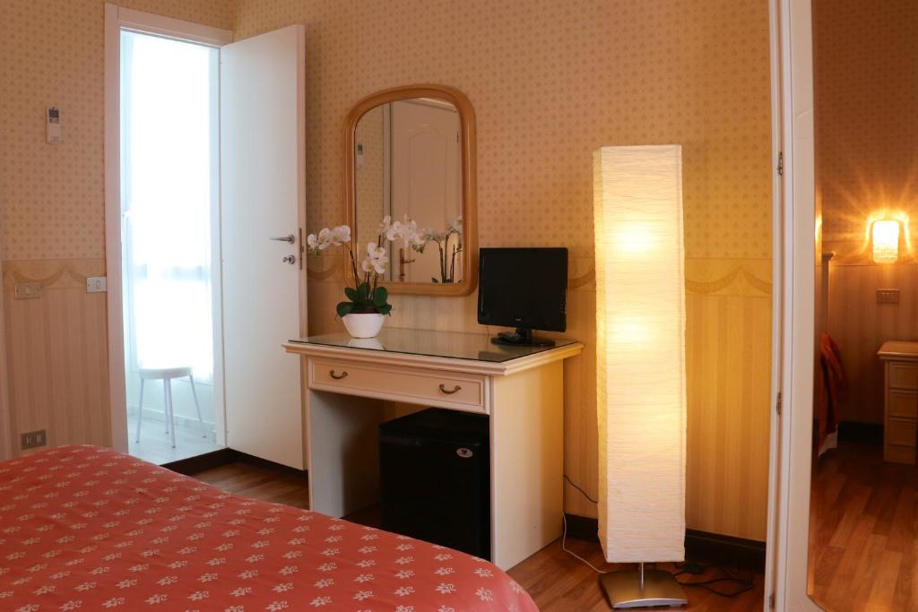 a bedroom with a desk with a computer and a mirror at Hotel Du Parc in Stresa