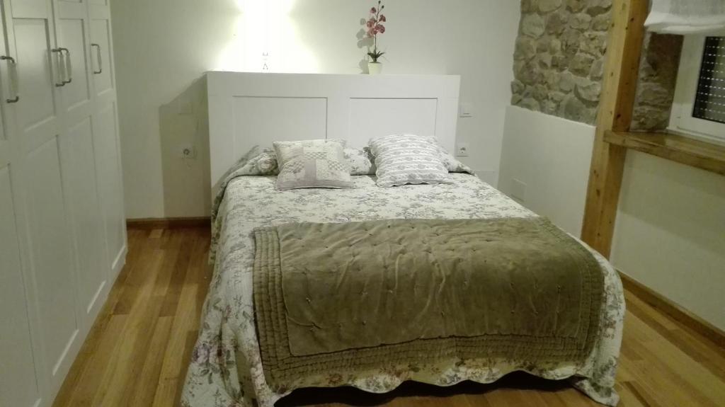 um quarto com uma cama com um edredão e almofadas em La Casa de Santa Olalla em Molledo