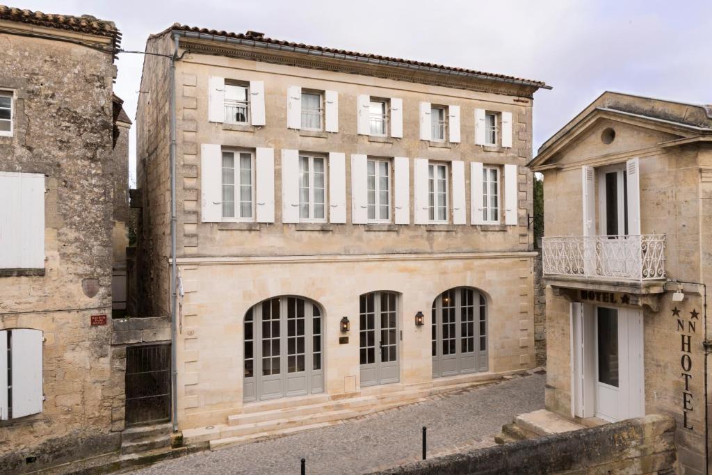 ein altes Gebäude in der Mitte von zwei anderen Gebäuden in der Unterkunft Auberge de la Commanderie in Saint-Émilion