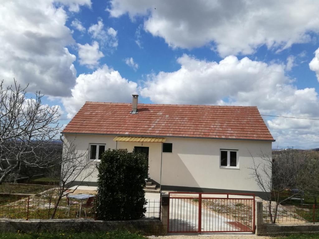 une maison blanche avec un toit rouge et une clôture dans l'établissement Kuća za odmor Mile, à Drniš