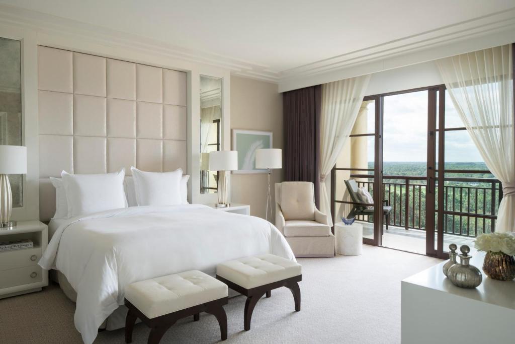 a bedroom with a large white bed and a balcony at Four Seasons Resort Orlando at Walt Disney World Resort in Orlando
