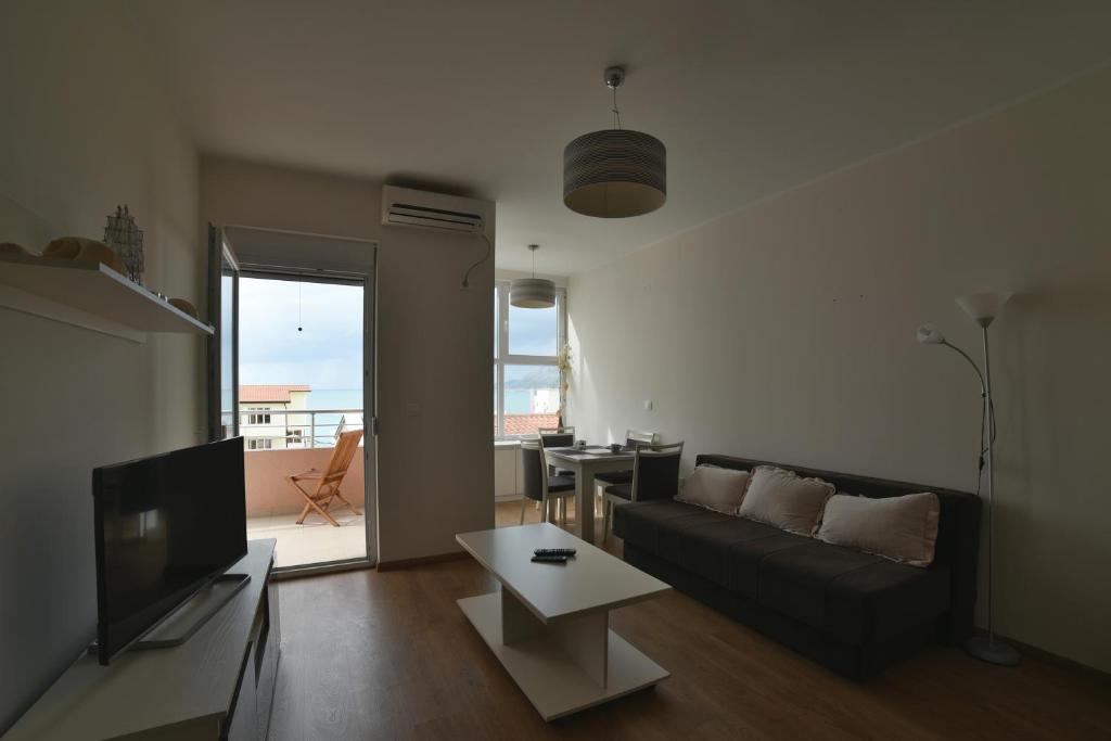 a living room with a couch and a tv and a table at Tuna Apartments in Dobra Voda