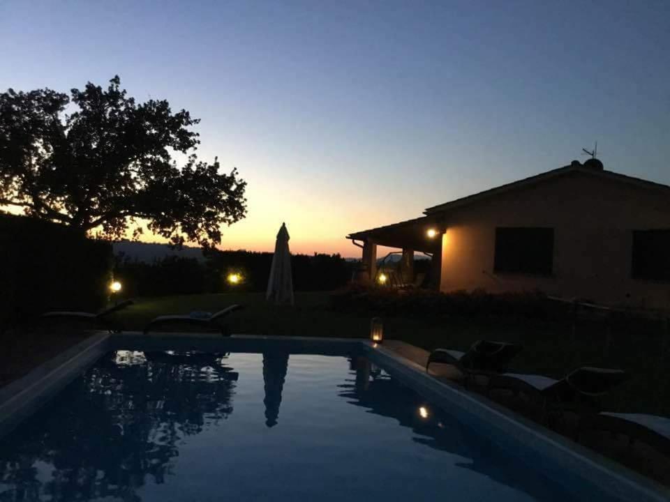 una piscina frente a una casa con puesta de sol en Le Siepi en Magliano in Toscana