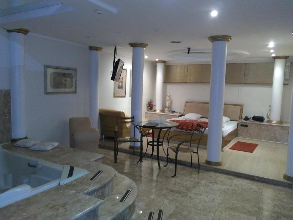 een woonkamer met een bed en een tafel en stoelen bij Heru's Motel in Poços de Caldas