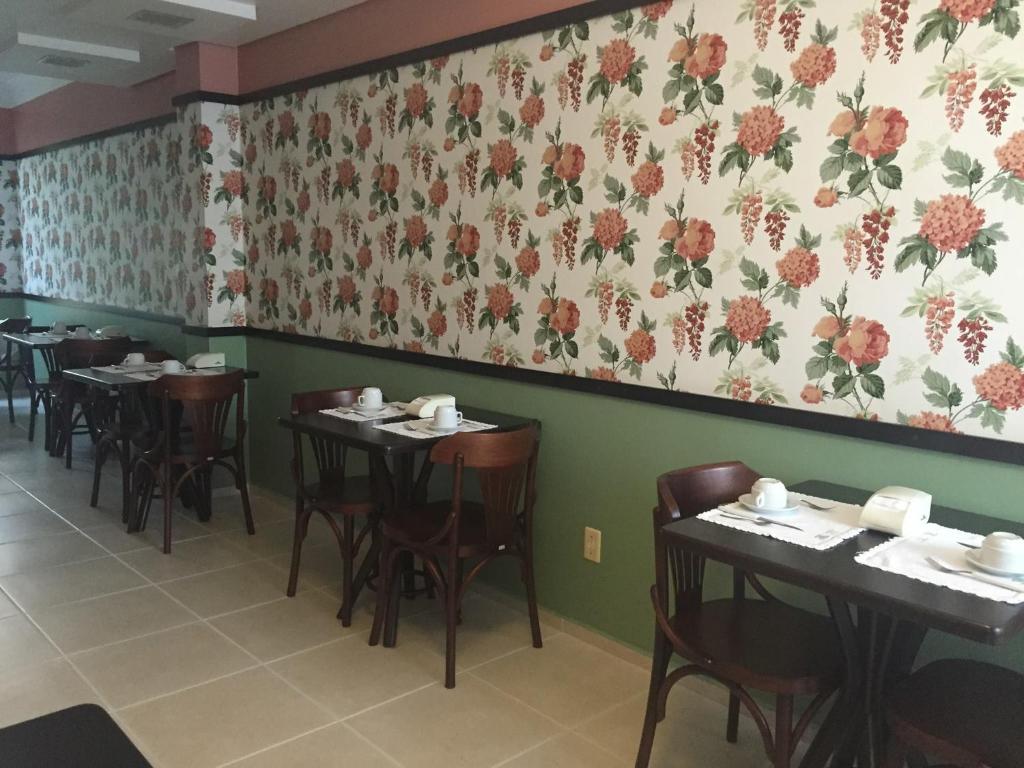 una sala da pranzo con tavoli, sedie e parete floreale di Hotel do Lago a Toledo