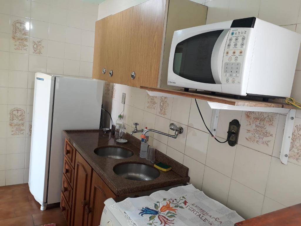 a kitchen with a sink and a microwave on a shelf at Apartamento no centro in Nova Petrópolis