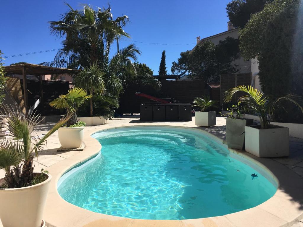 a swimming pool with palm trees in a yard at Villa Esterel Plage in Saint-Raphaël