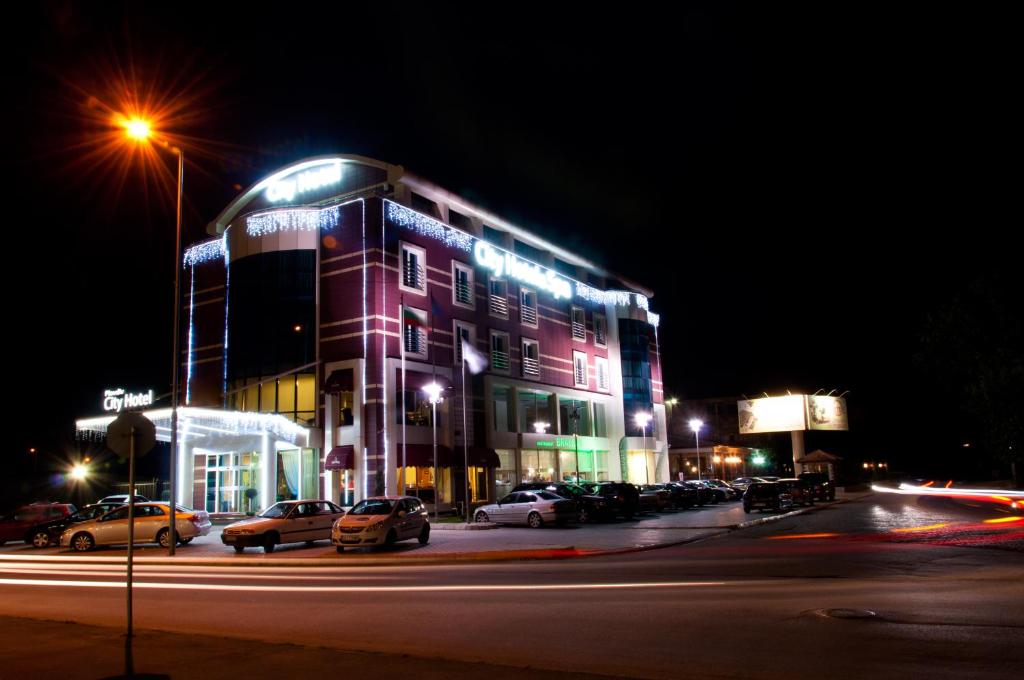 een gebouw met auto's geparkeerd op een parkeerplaats 's nachts bij City Hotel Plovdiv in Plovdiv