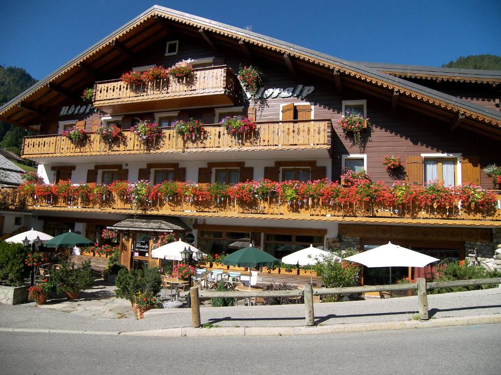 a large building with flowers and umbrellas in front of it at Hotel Floralp in La Clusaz