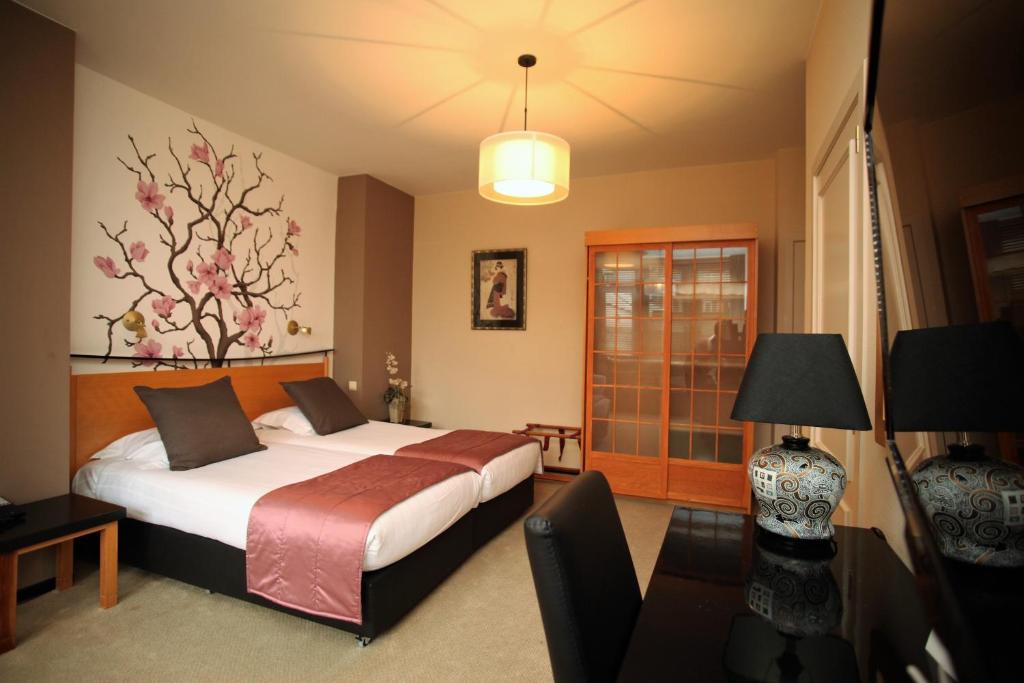 a bedroom with a bed and a table with a lamp at Hotel La Roseraie in Wemmel