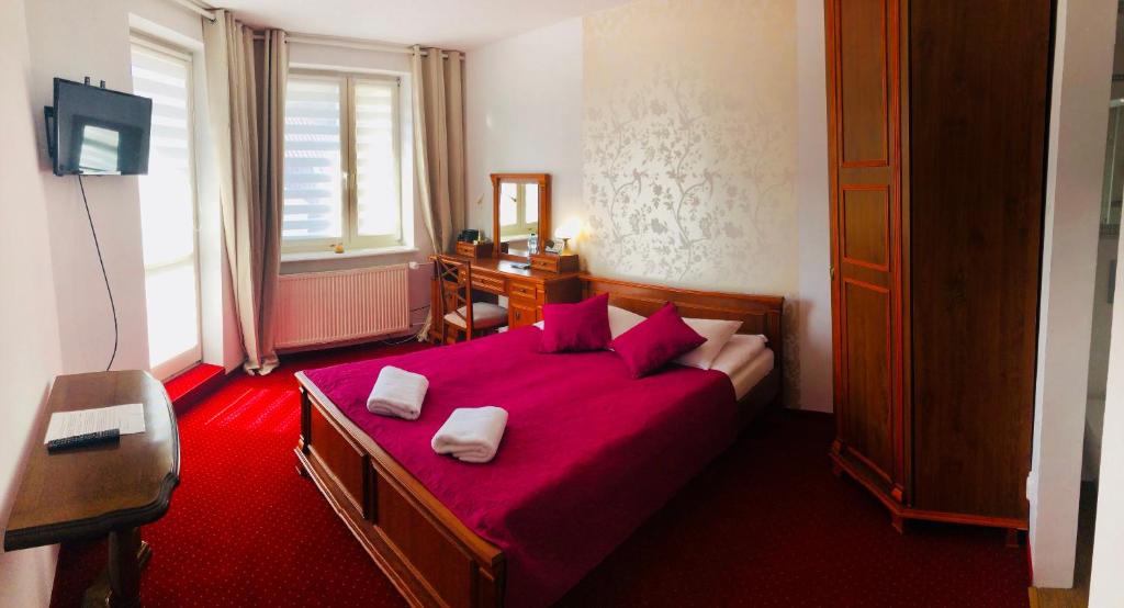 a bedroom with a red bed with two towels on it at Villa Kabbalah in Gdańsk