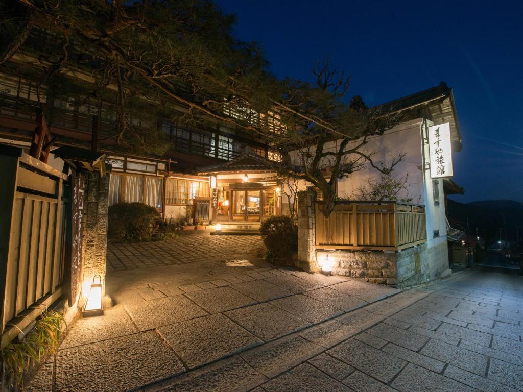 un bâtiment avec des lumières devant lui la nuit dans l'établissement Masuya Ryokan, à Aoki