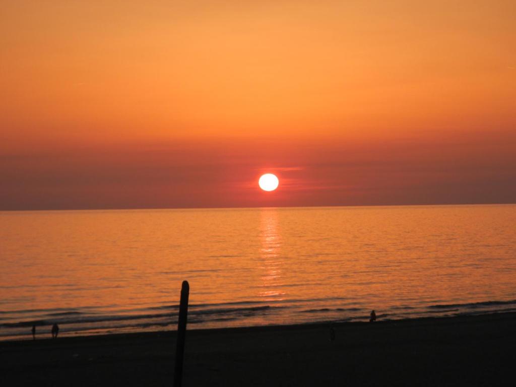 einen Sonnenuntergang am Strand mit Sonnenuntergang in der Unterkunft Attico Sulla Spiaggia in Viareggio