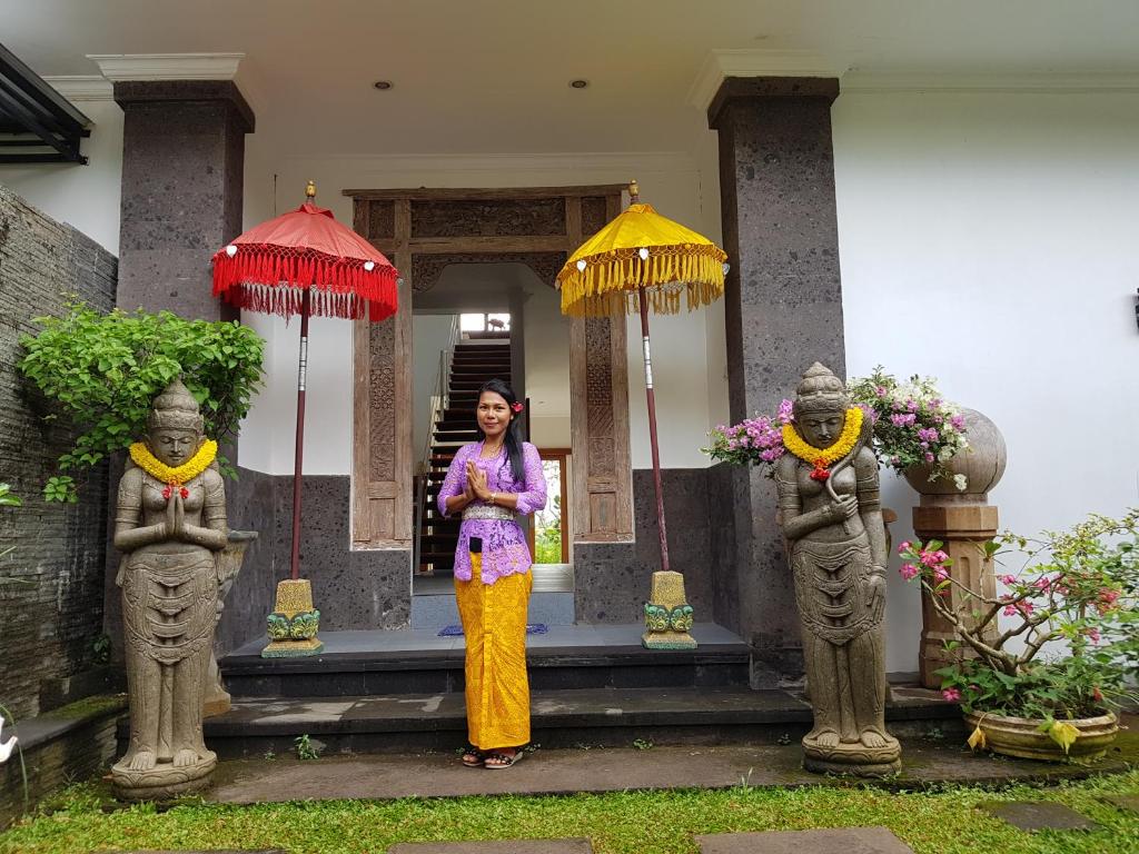 una mujer parada frente a un edificio con sombrillas en Villa Santai Karangasem, en Tirtagangga