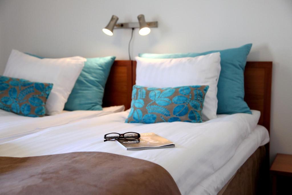 a pair of glasses on a bed with blue pillows at Hotell Conrad in Karlskrona