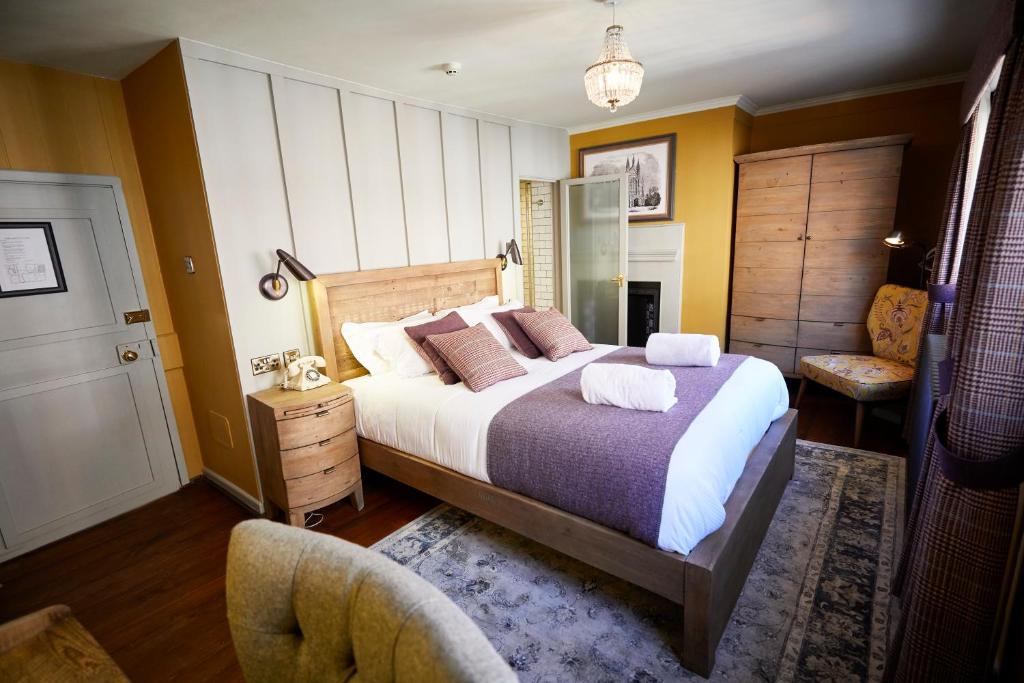 a bedroom with a large bed and a chair at Wykeham Arms in Winchester