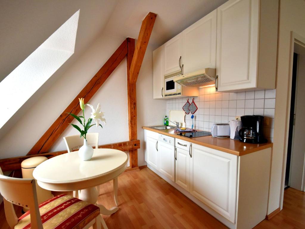 ビンツにあるFerienwohnung "Zum Postamt"の白いキャビネットと小さなテーブル付きのキッチンが備わります。