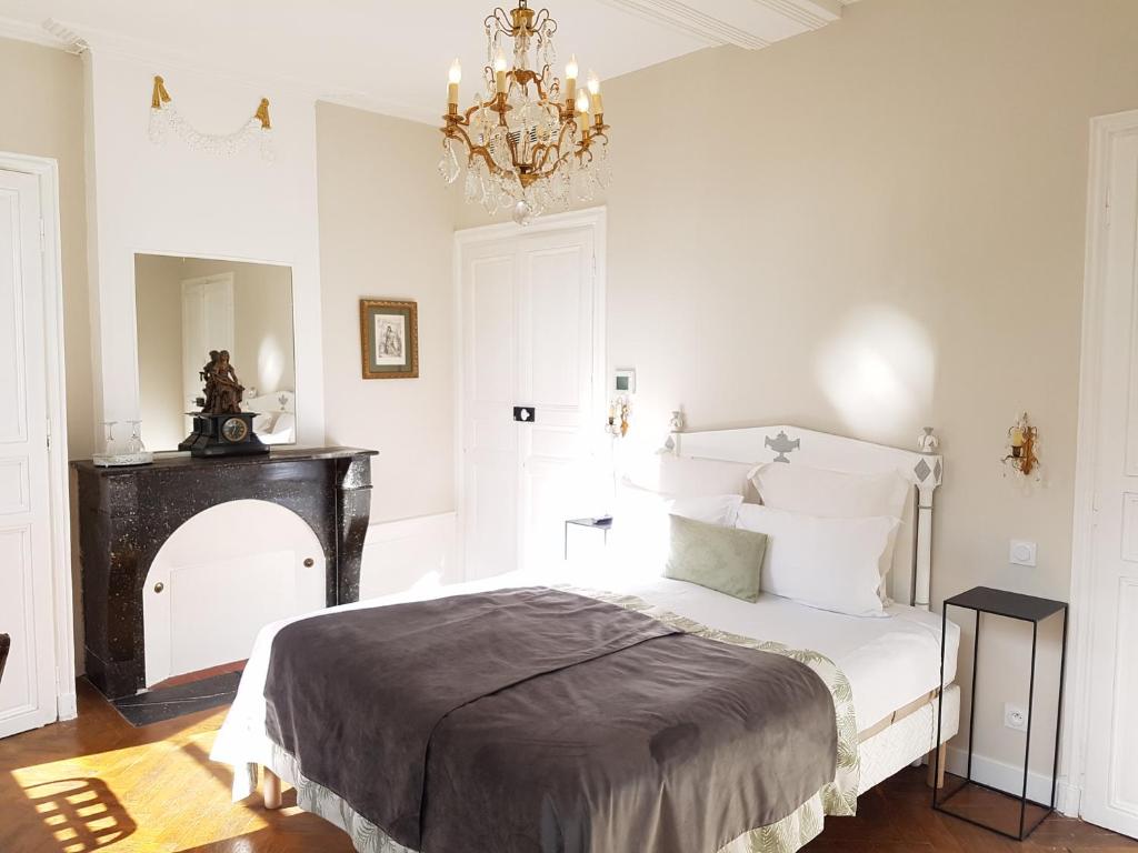 a white bedroom with a bed and a chandelier at Le Tardif, Noble Guesthouse in Bayeux