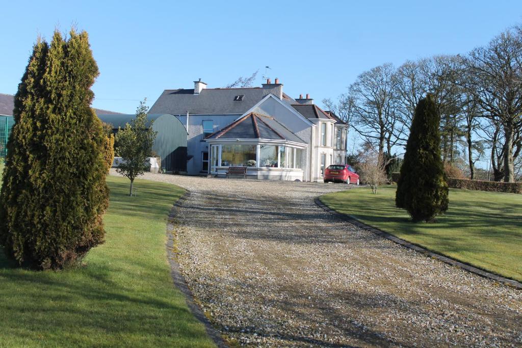 ein großes weißes Haus mit Kieseinfahrt in der Unterkunft Ballyhargan Farm House in Dungiven
