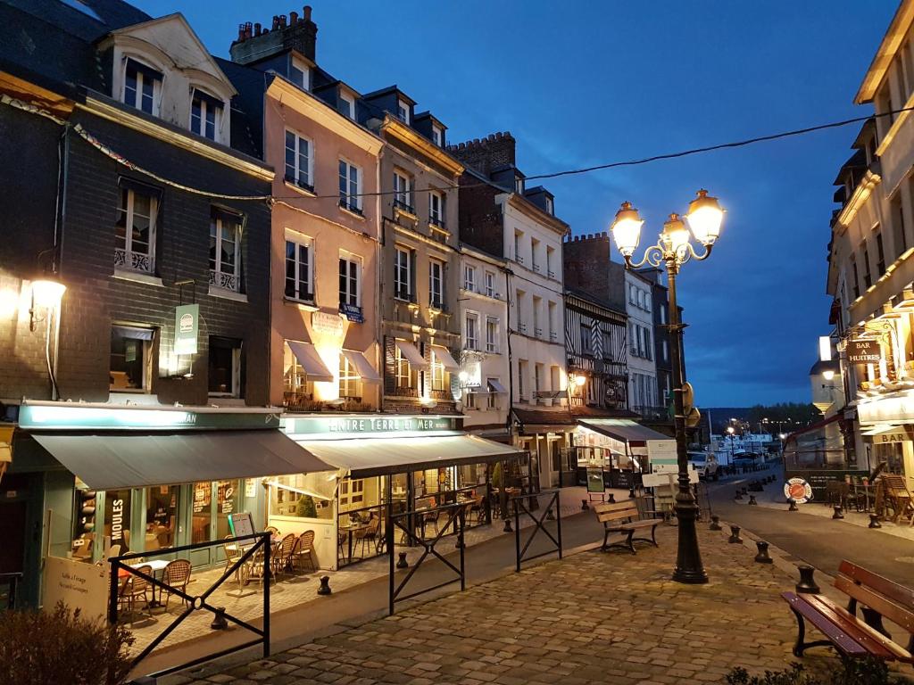 una calle de la ciudad por la noche con edificios y un semáforo en La Petite Parenthèse, en Honfleur