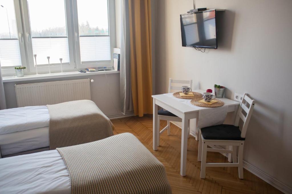 Cette petite chambre comprend une table, un lit et une télévision. dans l'établissement Rondo Mogilskie Apartment, à Cracovie