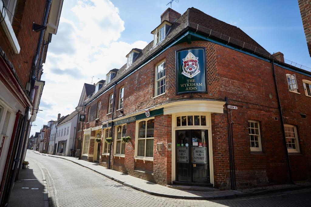 a brick building with a sign on it on a street at Wykeham Arms in Winchester