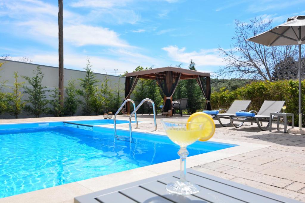 a swimming pool with a drink and a glass of wine at Elia Villa in Angeliana