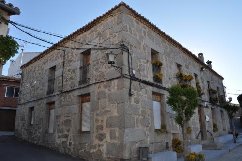 um antigo edifício de pedra ao lado de uma rua em Casa Rural los 4 Balcones em Hoyocasero