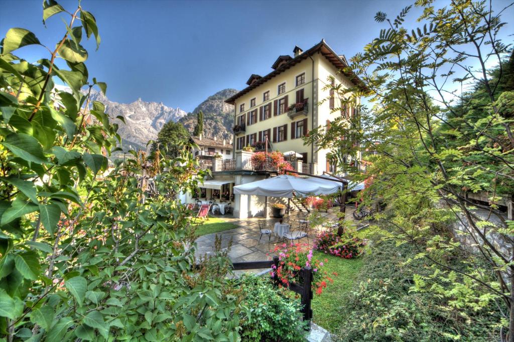 un hôtel avec un jardin en face d'un bâtiment dans l'établissement Villa Novecento Romantic Hotel - Estella Hotel Collection, à Courmayeur