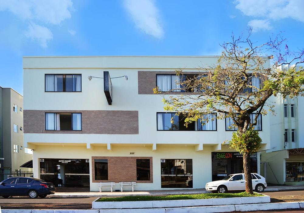 un gran edificio blanco con una sombrilla en el lateral. en Hotel Fiorini Ltda en Pinhalzinho