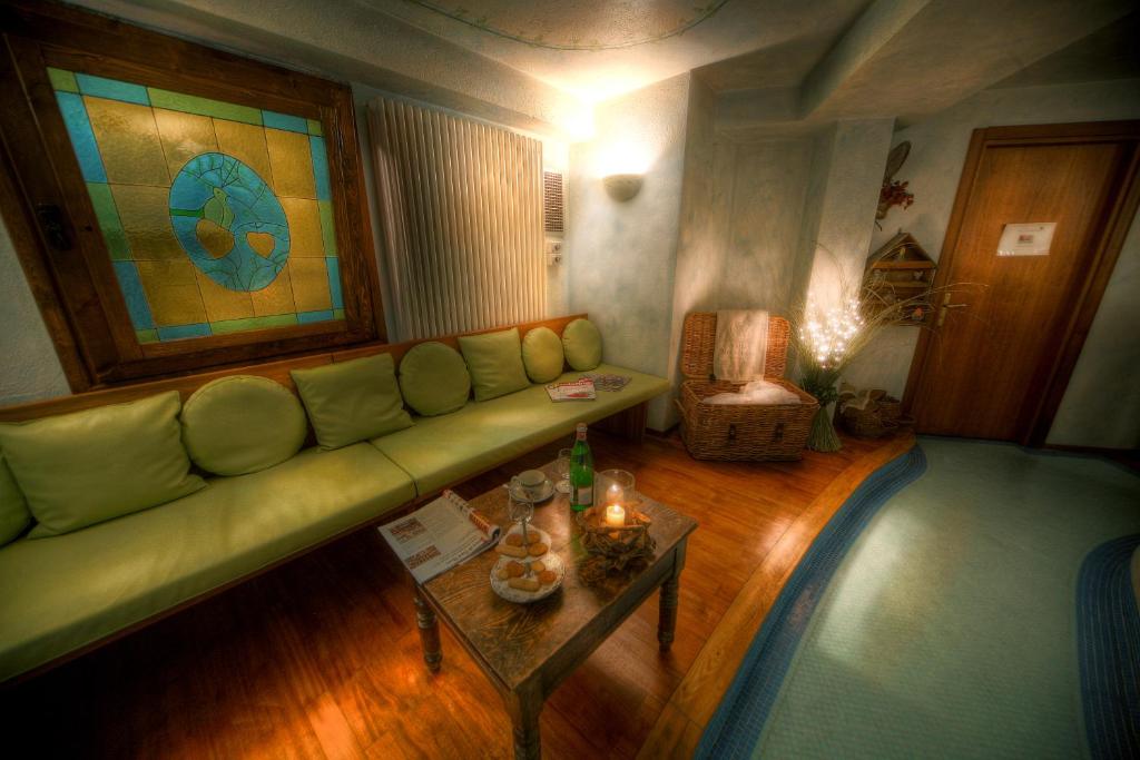 a living room with a green couch and a table at Villa Novecento Romantic Hotel - Estella Hotel Collection & Experience in Courmayeur