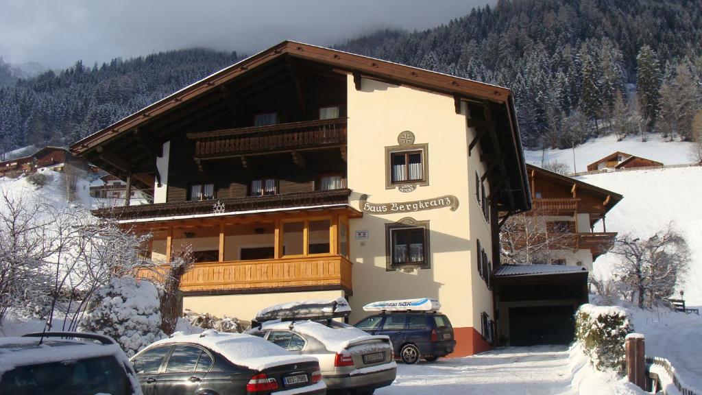 un bâtiment avec des voitures garées à l'extérieur sous la neige dans l'établissement Haus Bergkranz, à Neustift im Stubaital