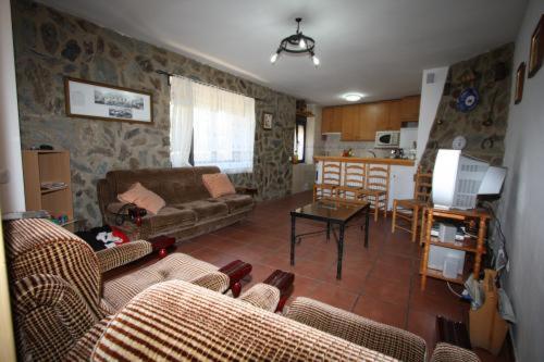 sala de estar con sofá, mesa y cocina en Casa Rural el Huerto, en Solana de Ávila