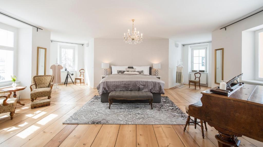 a large white bedroom with a bed and a piano at Apartments Hoferhaus in Bad Aussee