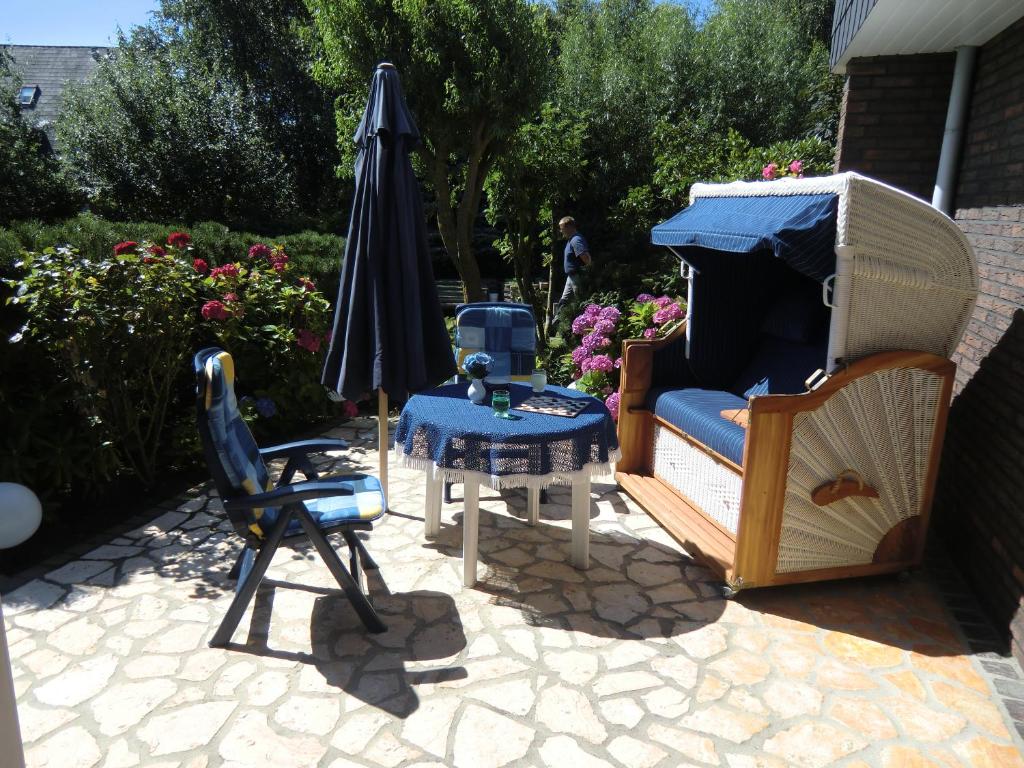 une terrasse avec un parasol, une table et des chaises dans l'établissement Fewo Jutta Bönisch, à List auf Sylt