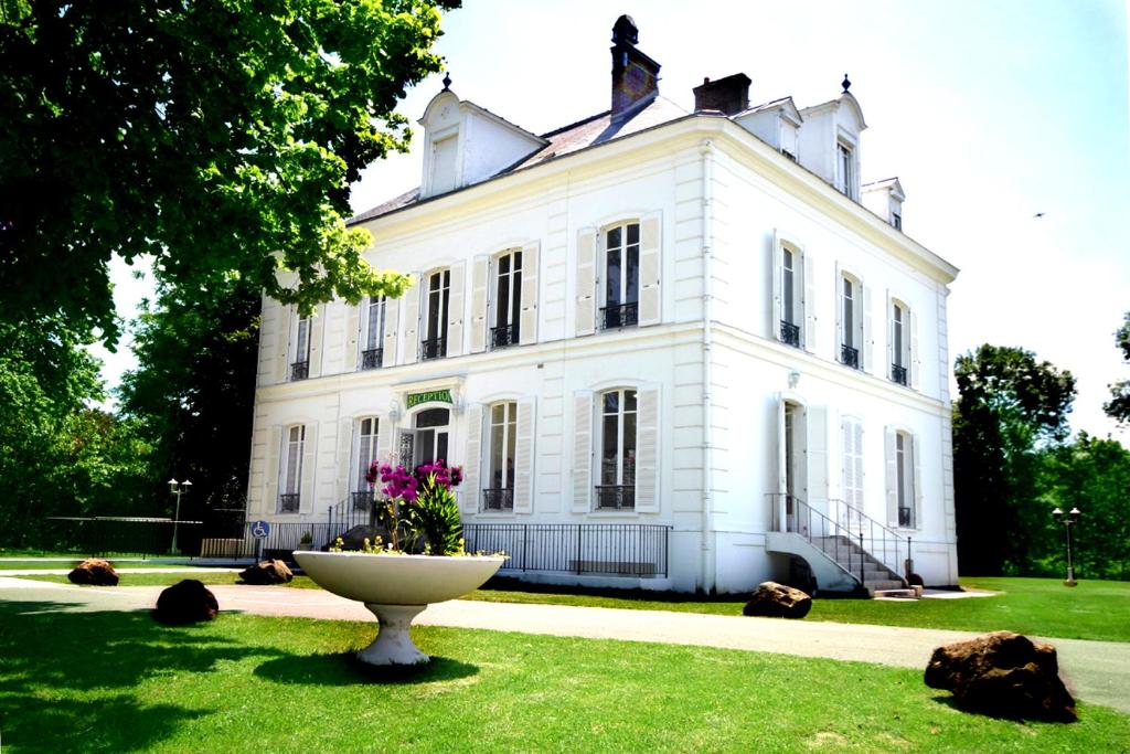 um grande edifício branco com uma fonte em frente em Logis - Hostellerie Le Chatel Nangis em Nangis