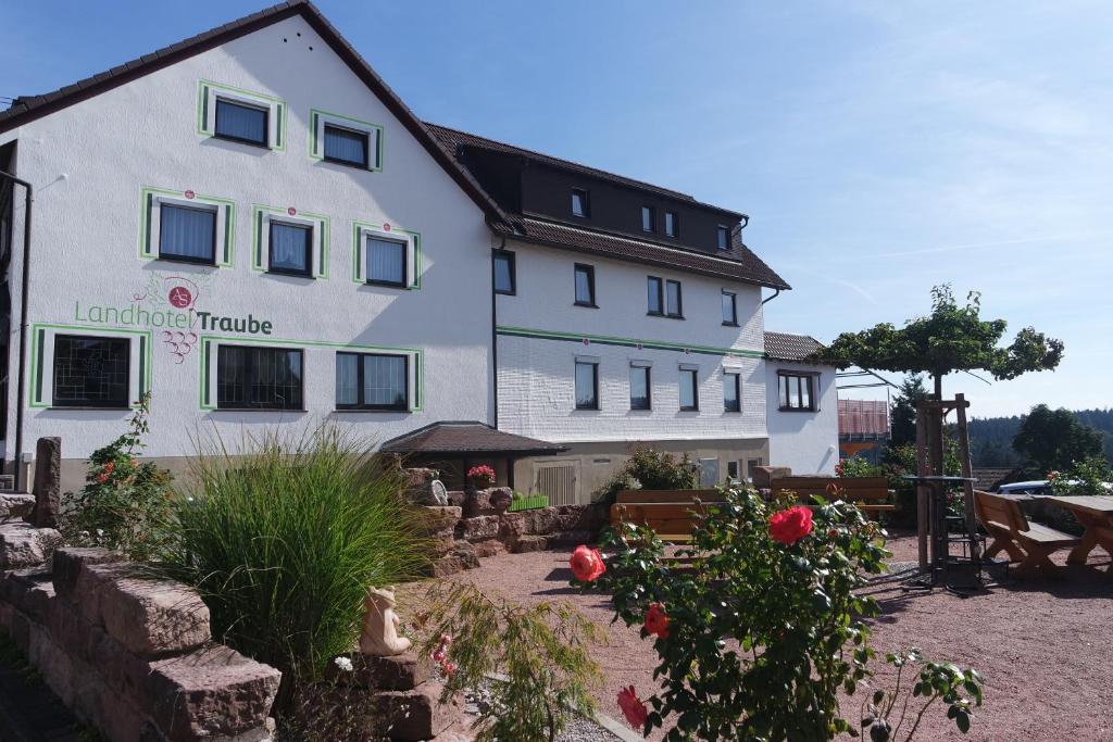 a large white building with a garden in front of it at Landhotel Traube in Seewald