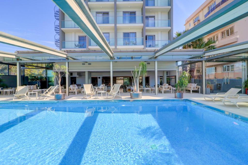 een zwembad met stoelen en een gebouw bij Palace Hotel Glyfada in Athene
