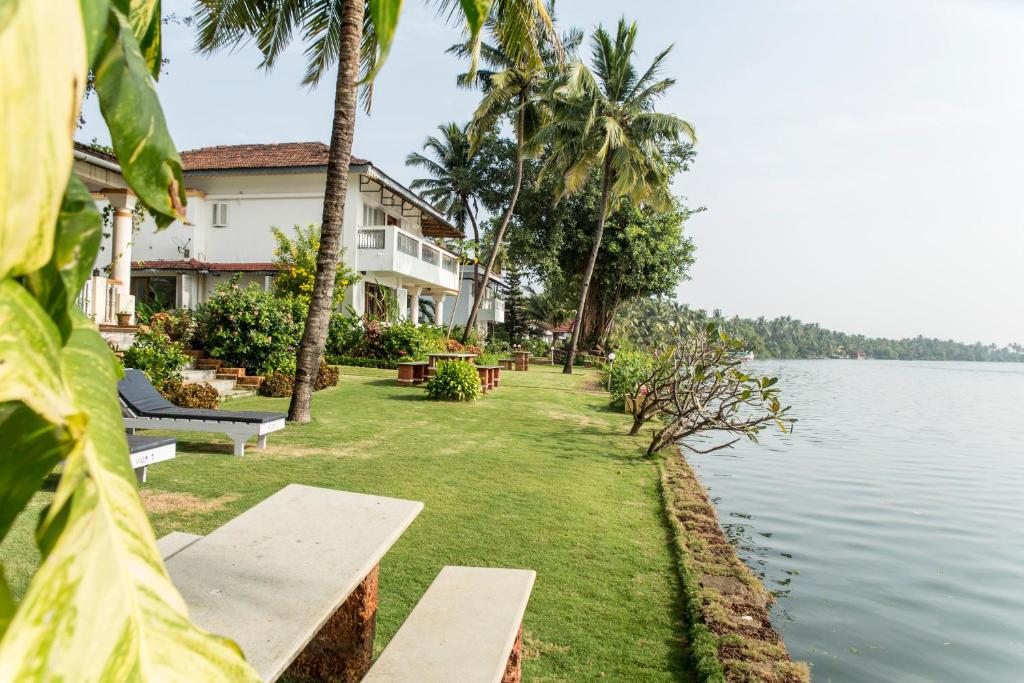 a house with benches next to a body of water at Shikara Beach Resort in Cavelossim