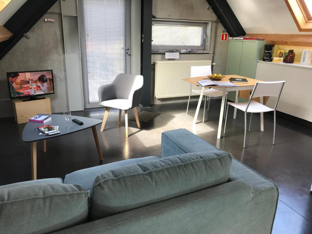 ein Wohnzimmer mit einem Sofa, einem Tisch und Stühlen in der Unterkunft Rap 'n Holiday Home in Sint-Denijs-Westrem