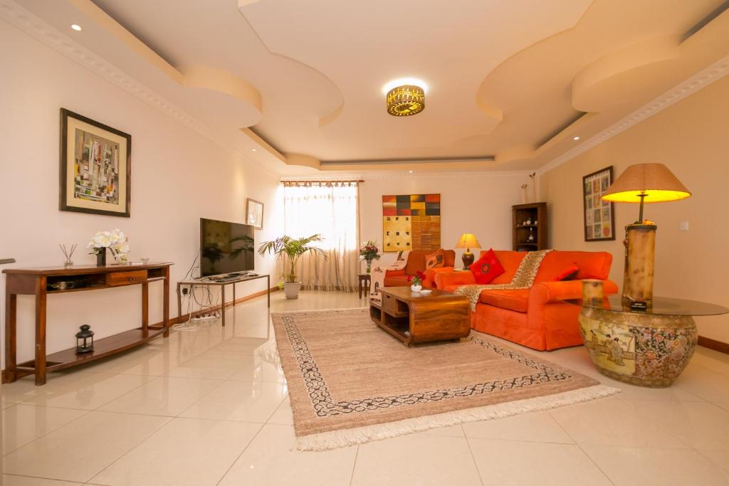a living room with an orange couch and a table at Hotel Rudi in Nairobi