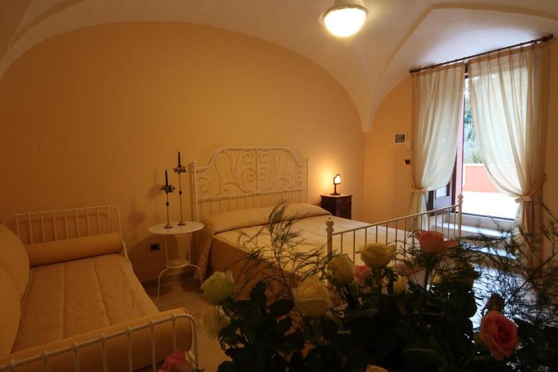 カザラーノにあるB&B Ippocastanoのベッドルーム1室(ベッド1台、ソファ、窓付)