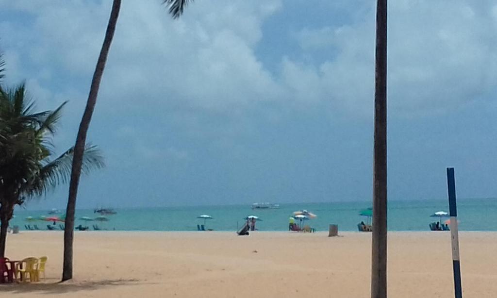 una playa con palmeras y el océano con sombrillas en Flat no melhor do Cabo Branco, en João Pessoa