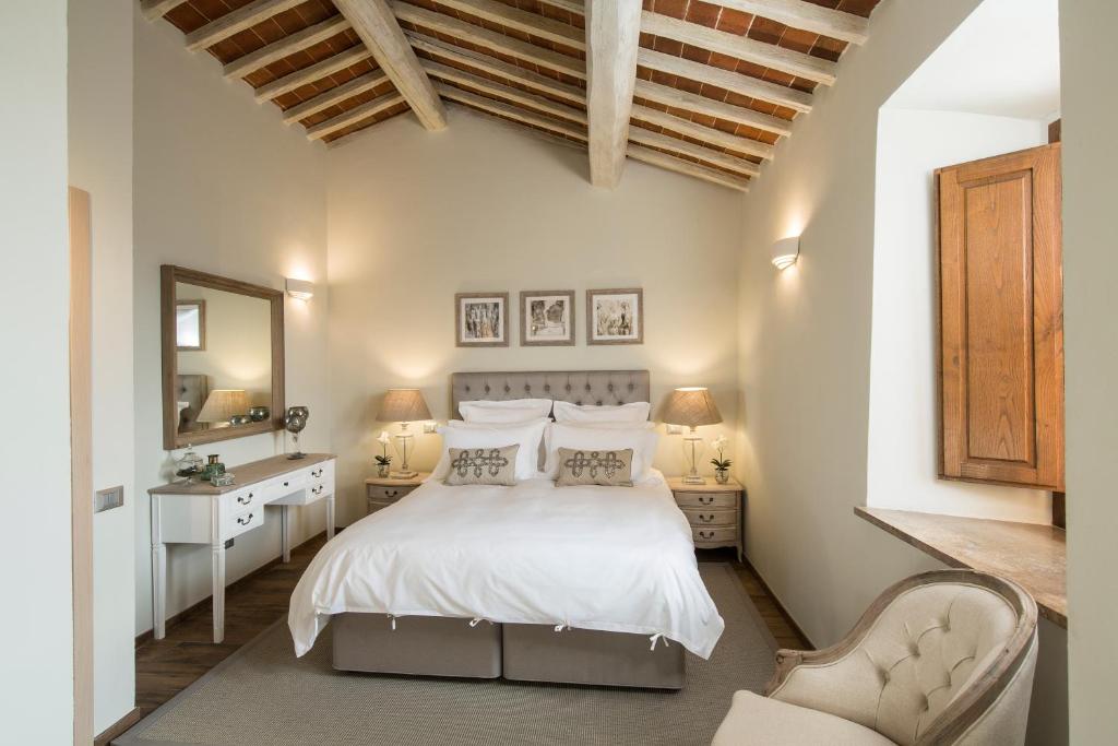 a bedroom with a white bed and a mirror at Borgo Argiano in Castelnuovo Berardenga