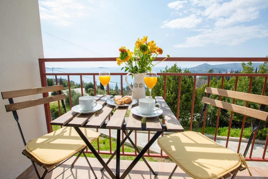 een tafel met twee stoelen en twee glazen sinaasappelsap bij Villa Pergola-Apartment Toni in Mlini