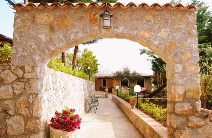 an archway in a stone wall with a bench and flowers at Residence Martina in Marina di Camerota
